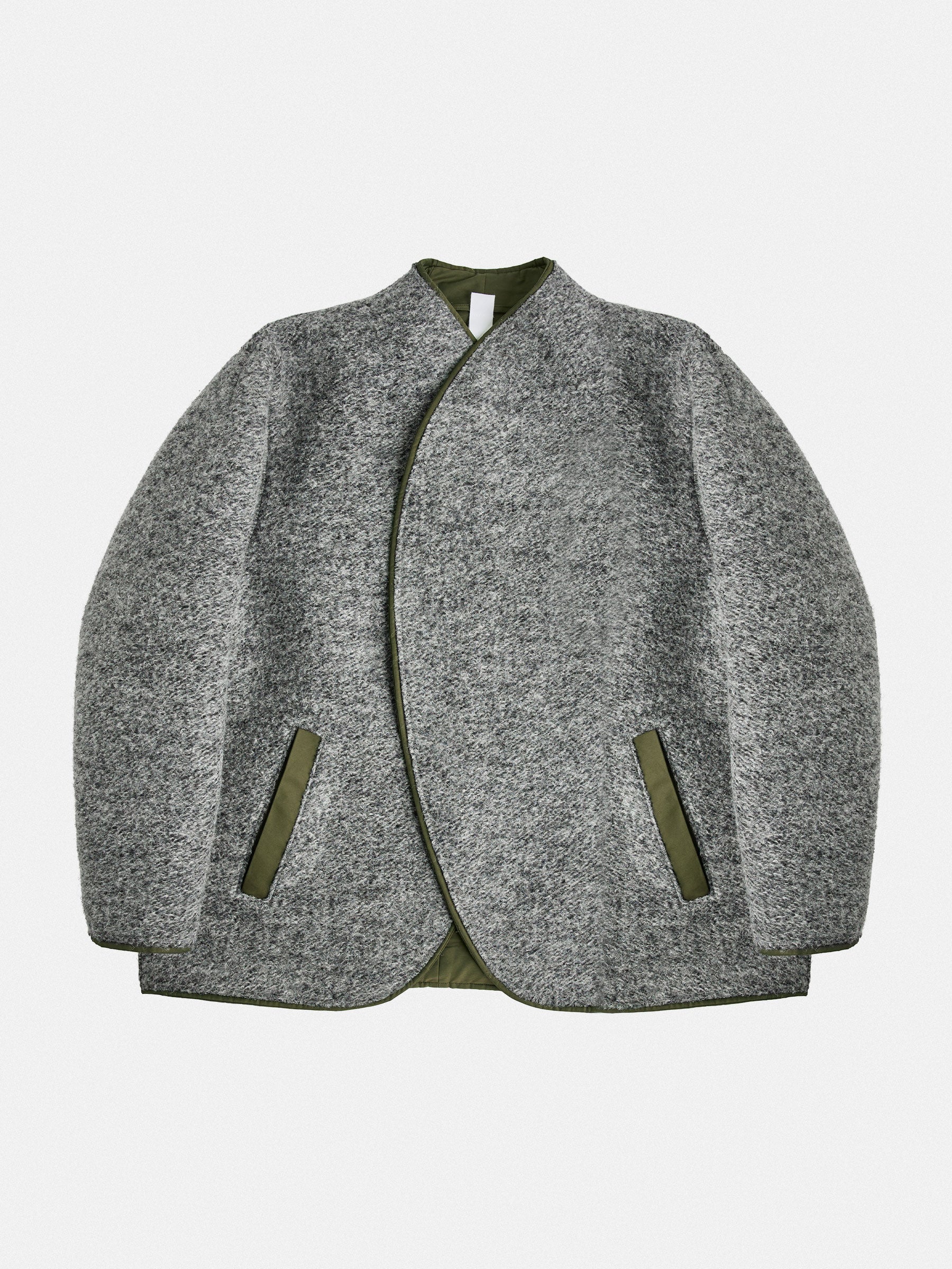 A versatile reversible jacket in grey/dark navy melange, featuring contrasting welt pockets. Its collarless design is shaped with darts for a refined neckline and structured shoulders. The interior mirrors the construction with added patch pockets. Precision piping unites both layers, reinforcing durability and design.
Outer: 80% Wool, 20% Polyester
Reverse: Cotton gabardine (58% Cotton, 38% Polyamide) with a light PU finish in army green
Closure: 8mm gunmetal zipper