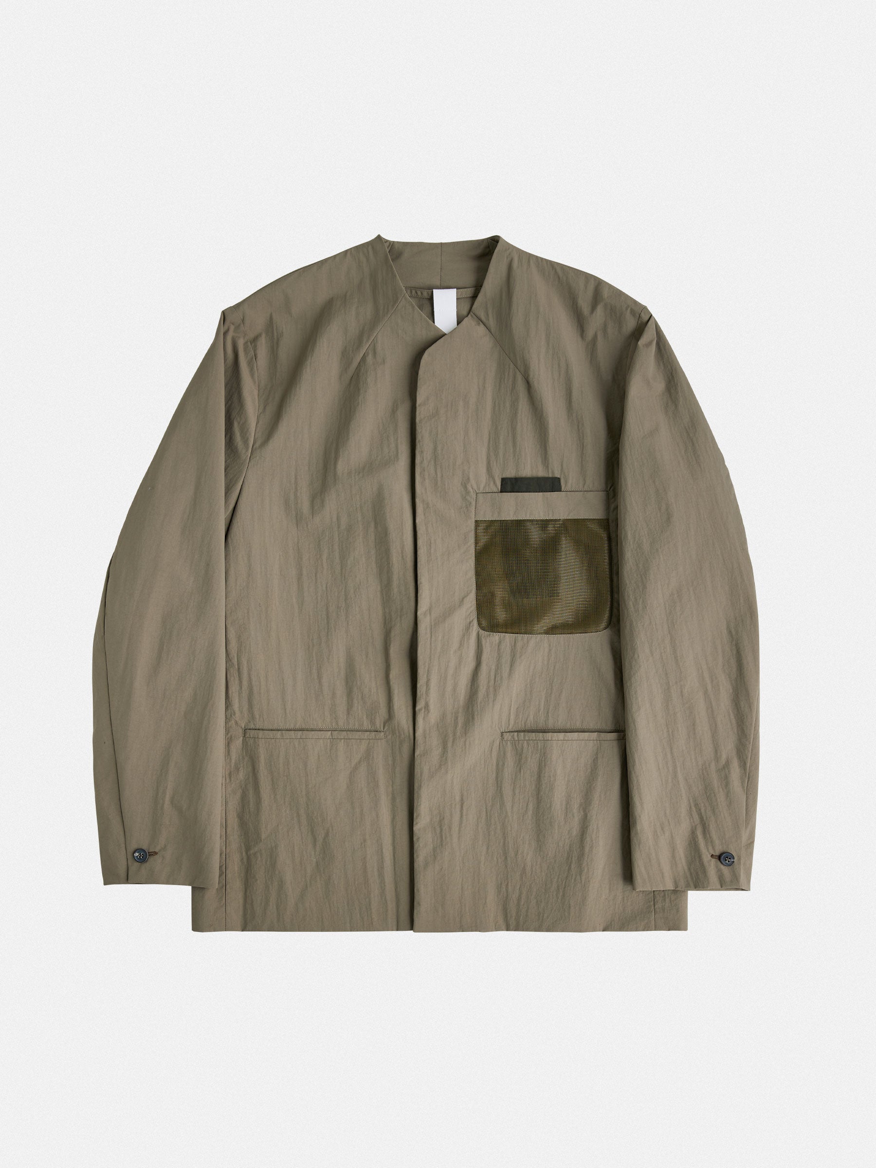 A tailored, collarless blazer with concealed closures and structured contrast chest pockets, balancing minimalism and technical precision.