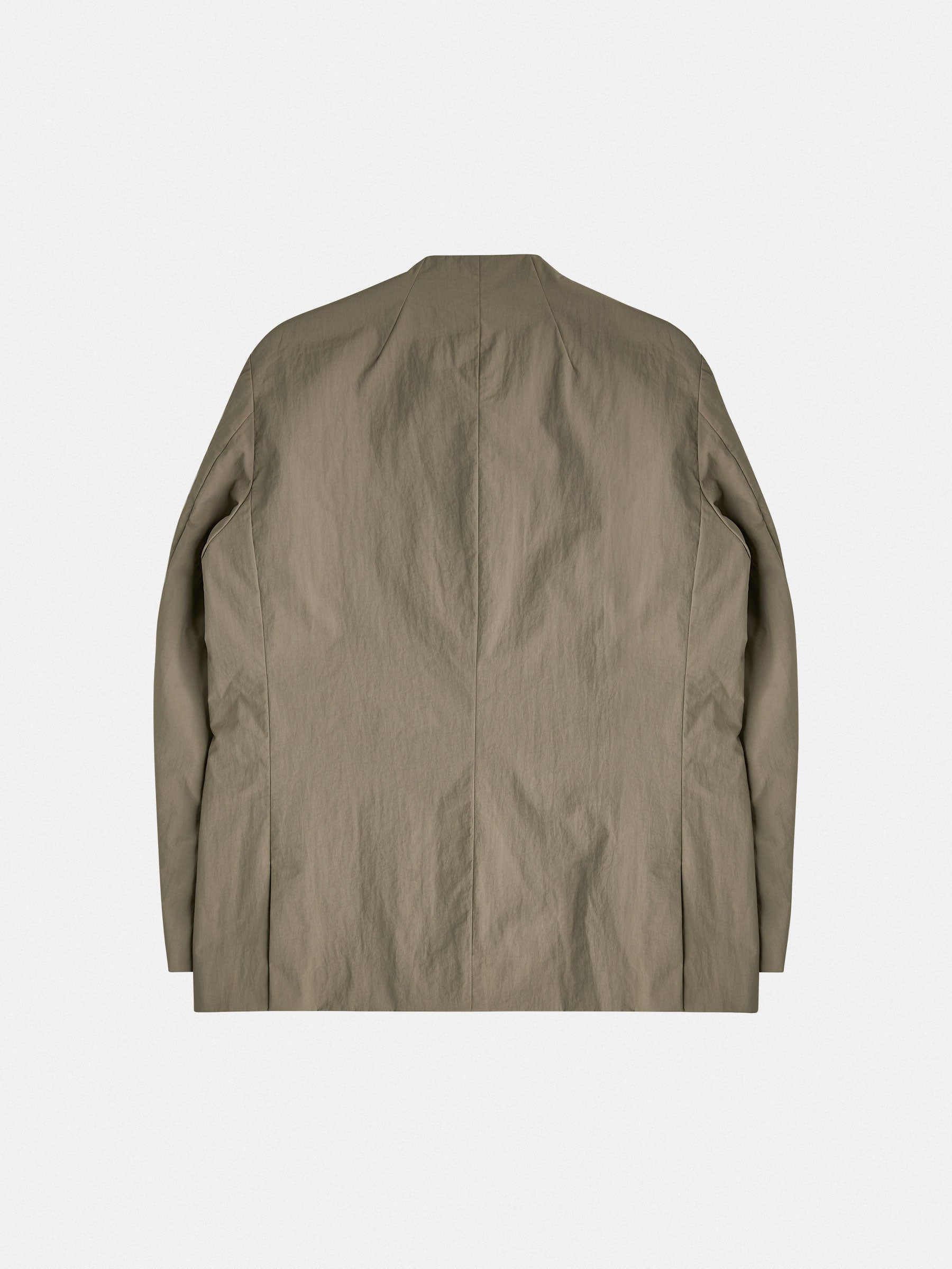 A tailored, collarless blazer with concealed closures and structured contrast chest pockets, balancing minimalism and technical precision.