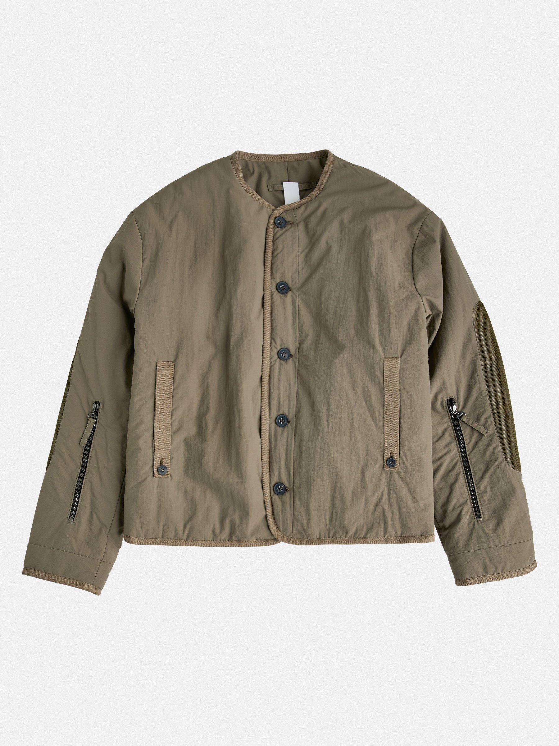 Lightweight insulated liner with a down-like feel, enhanced with mesh elbow details and contrast tape accents. Functional elements include vintage horn button closure and dual zippered lower-arm pockets.
Outer: 100% Recycled Polyamide
Lining: 100% Recycled Polyester (GRS-certified)
Fill: 60% Recycled PET, 40% Polyamide – sustainable down alternative
Details: 100% Recycled Cotton tape trim