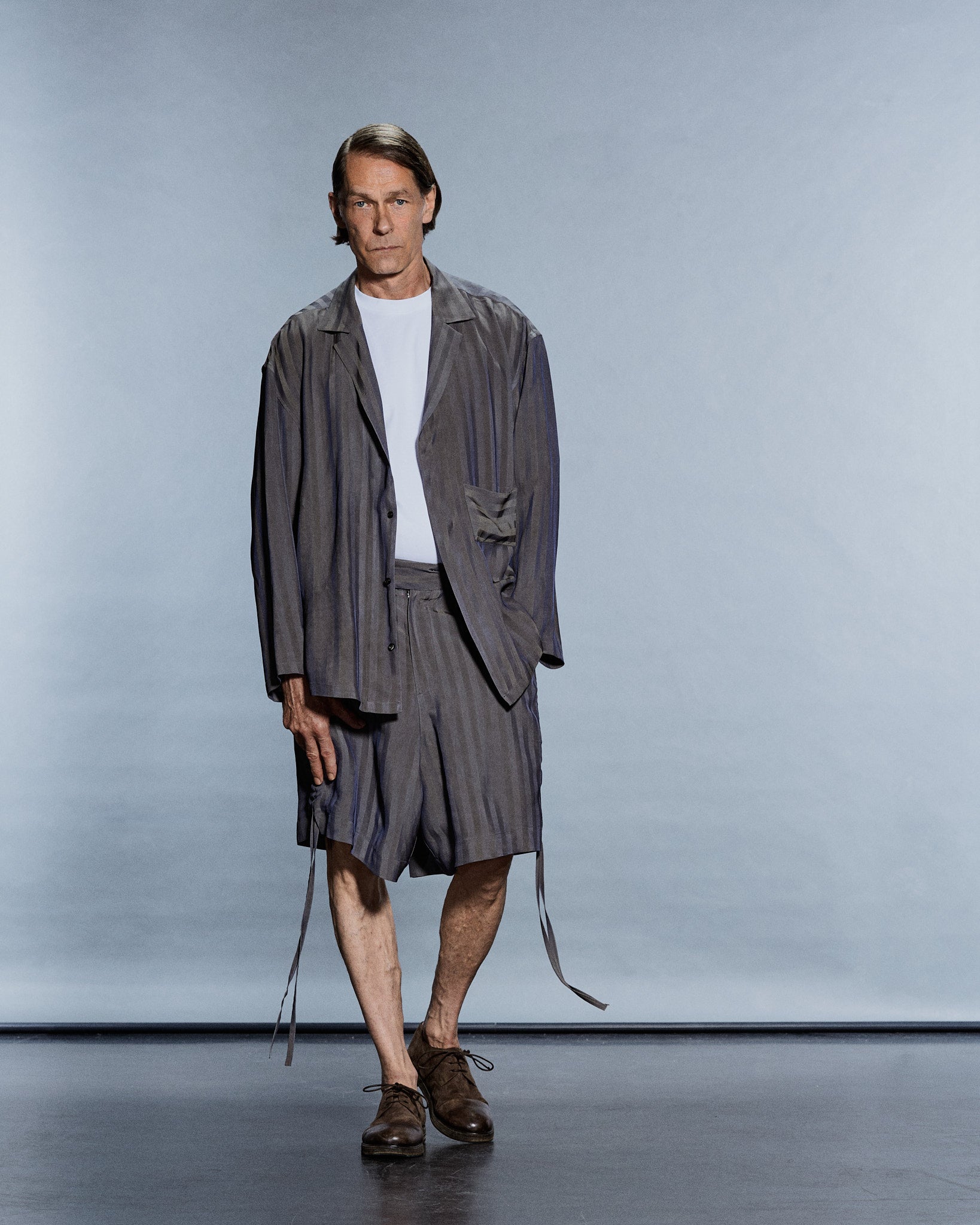 Full-length view of an oversized grey vertical-stripe shirt-jacket and matching tailored shorts — GABRIELSTUNZ APLOMB SS27.