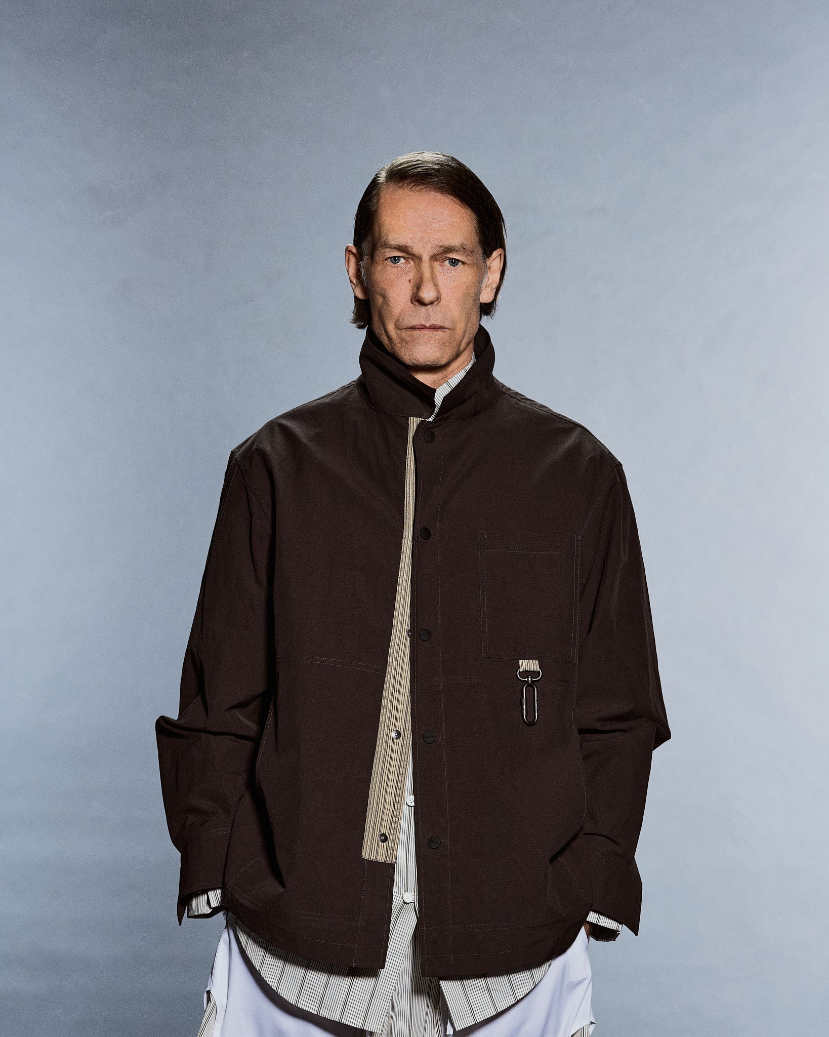 Portrait of a boxy brown stand-collar overshirt with snap front and chest pocket — GABRIELSTUNZ APLOMB SS27.