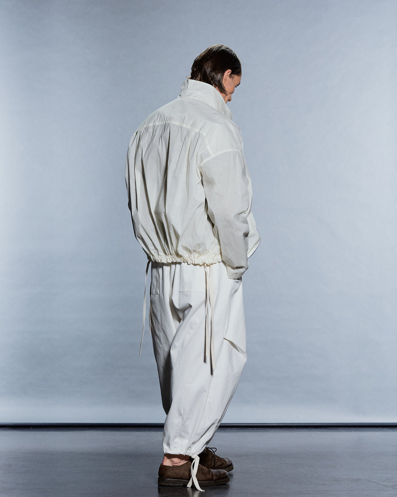 Rear view of a gathered cream cotton blouson and matching wide trousers with drawstring hems — GABRIELSTUNZ APLOMB SS27.